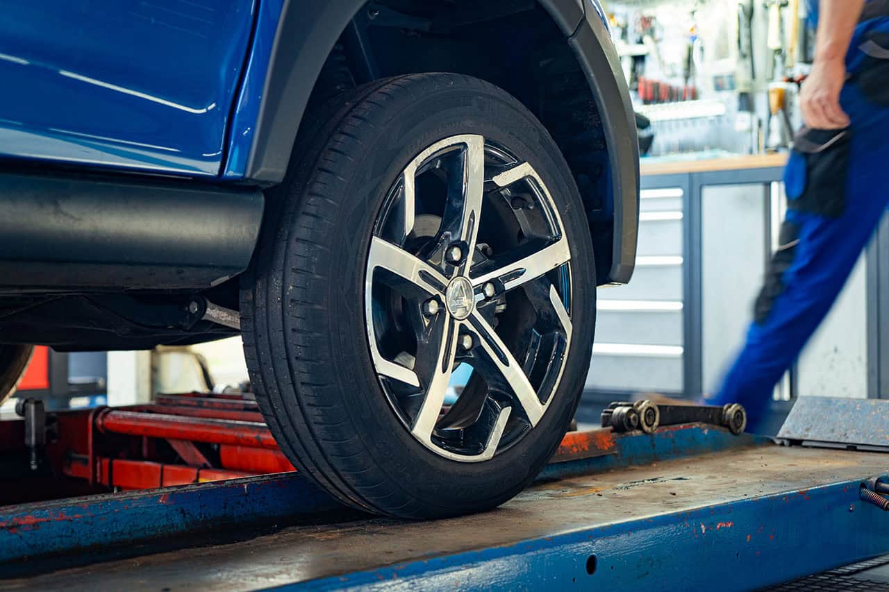 - 2. Moderne auto op autolift met gepolijste wielen en banden, auto reparatie of onderhoud in werkplaats.