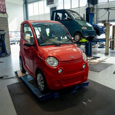 Mini elektrische auto in werkplaats voor onderhoud en reparatie. Compact elektrisch voertuig klaar voor service, ideaal voor stadsritten en milieuvriendelijk vervoer. Perfect voor klanten die duurzame mobiliteit zoeken.