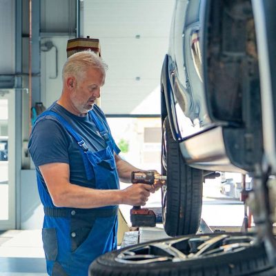 Werkplaatservice bij Vos Minicars, monteur controleert auto banden en velgen. Professionele auto-onderhoudsdiensten voor kleine auto's en minicars in Nederland.