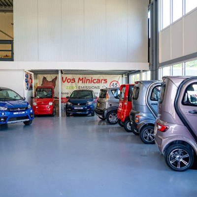 Kleine elektrische auto’s en minibikes in showroom van Vos Minicars, gespecialiseerd in emissievrije stadsauto’s en compacte elektrische voertuigen voor milieuvriendelijk vervoer.